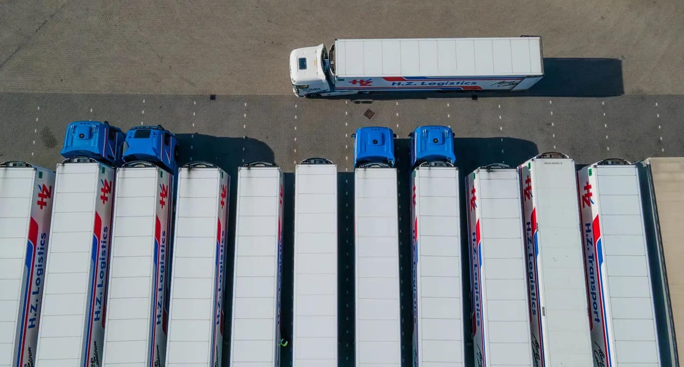 Lastbilar uppställda på en logistikanläggning sedda uppifrån
